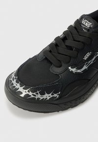 Sneaker neri Vans con tomaia in sintetico testurizzato, lacci neri e motivo a punte metalliche argento sul lato. Suola in gomma con battistrada strutturato.