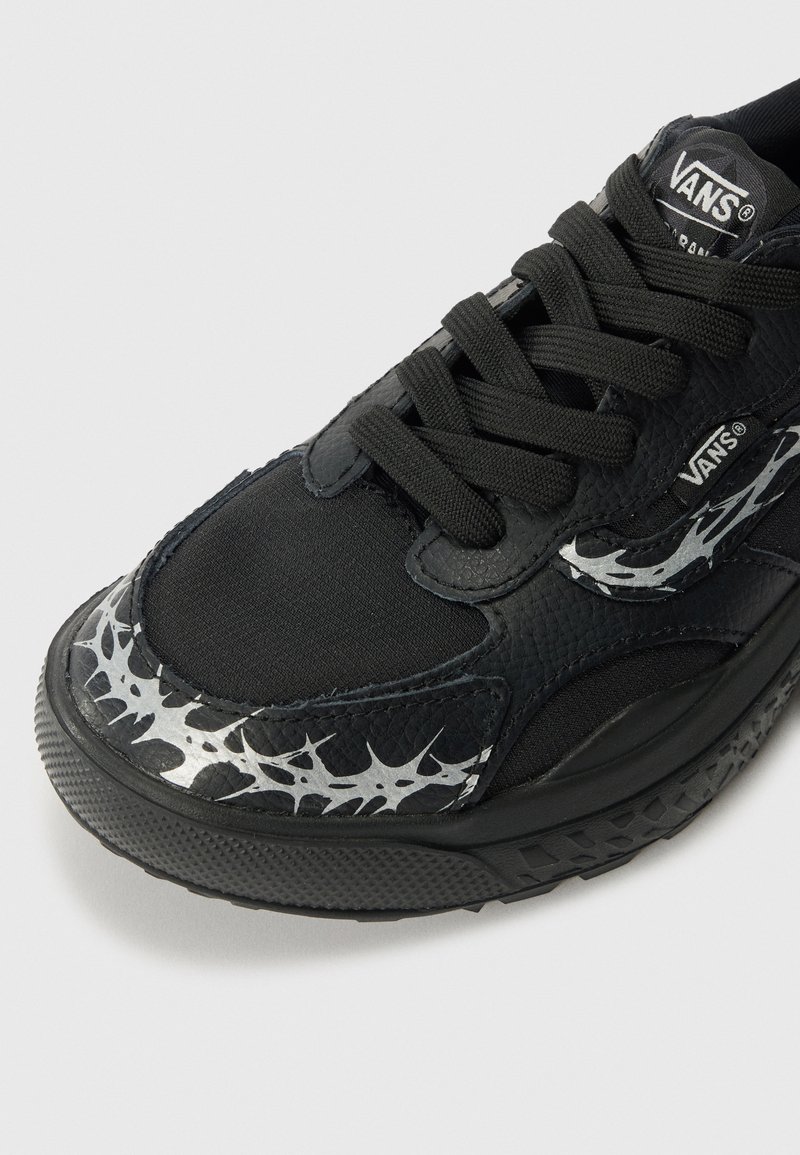 Sneaker neri Vans con tomaia in sintetico testurizzato, lacci neri e motivo a punte metalliche argento sul lato. Suola in gomma con battistrada strutturato.