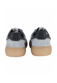 Sneaker grigie in suede con una suola leggera e marrone strutturata. Presentano accenti neri sul tallone e un retro liscio. Design minimalista.