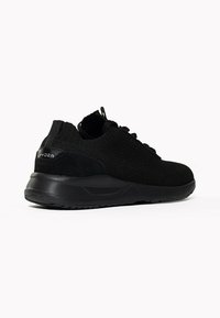 Sneaker nera con una toma in maglia tessurizzata e un accento in suede. Presenta una silhouette elegante con una suola in gomma resistente e chiusura con lacci.