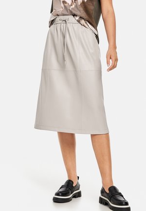 Lichtgrijze leren midi-rok met een elastische tailleband en trekkoord. Voorzien van verticale naden en een gladde textuur. Gecombineerd met zwarte schoenen.