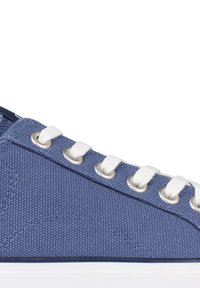 Zapatilla de lona azul con cordones blancos, ojales plateados y un upper texturizado. La suela es blanca, con un ribete azul que contrasta.