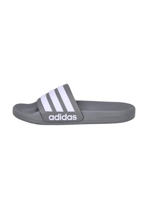 Sandalia tipo slide gris Adidas con tres franjas blancas y el logo de Adidas en la correa, mostrada de perfil sobre un fondo blanco.