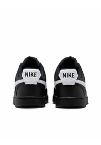 Sneakers atletiche nere con una finitura liscia, accenti bianchi e una linguetta sul tallone firmata con la scritta in grassetto "NIKE".