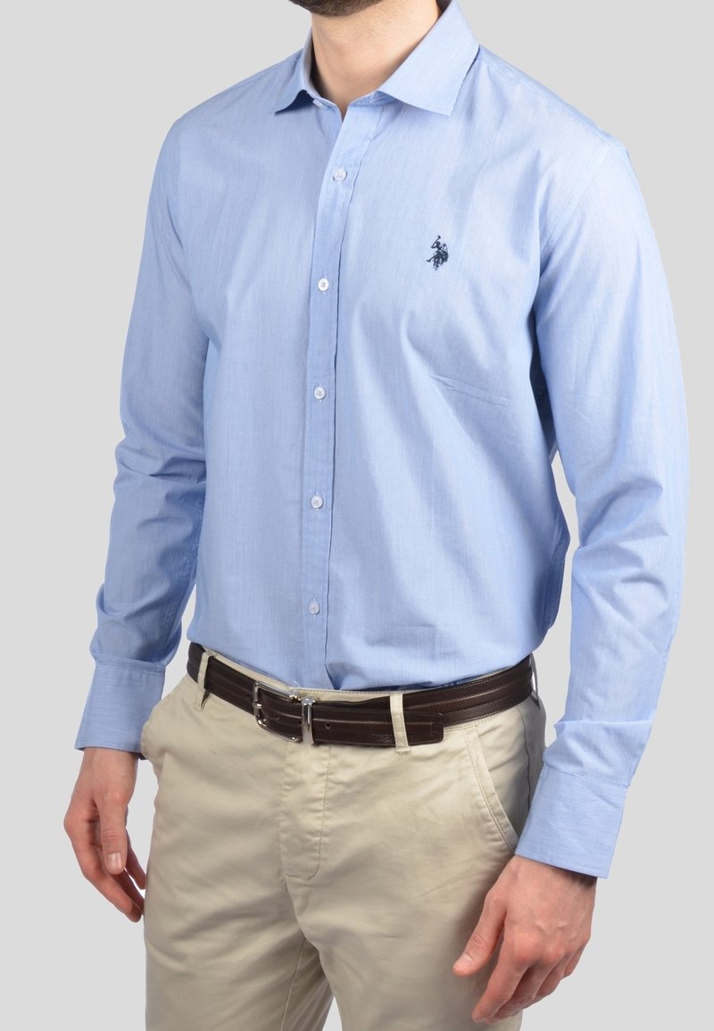Camicia azzurra chiara in cotone con una texture liscia, caratterizzata da un piccolo logo navy sul petto e maniche lunghe.