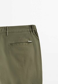 Zielone oliwkowe spodnie z teksturowanej tkaniny, z tylną kieszenią z zamkiem błyskawicznym oraz małym metalowym akcentem logo.