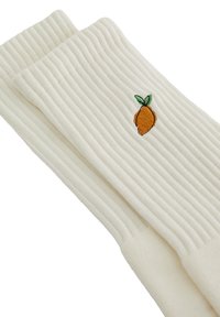 Ribbad elfenbensfärgade strumpor med en liten broderad apelsin med gröna blad. Mjuk textur som passar för avslappnad användning.