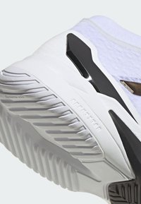 Białe buty sportowe z teksturowaną cholewką, z falistą gumową podeszwą i czarnymi akcentami w okolicach pięty i śródstopia dla wsparcia.
