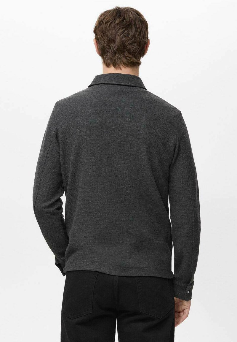 Dunkelgraues Langarmhemd mit Kragen, strukturierter Stoff und einer Knopfapplikation an der Manschette, von hinten gesehen.