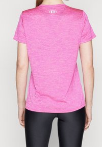 Rosa träningströja med kort ärm och melerad textur, med en liten vit logotyp på den övre ryggen; matchad med svarta tights.