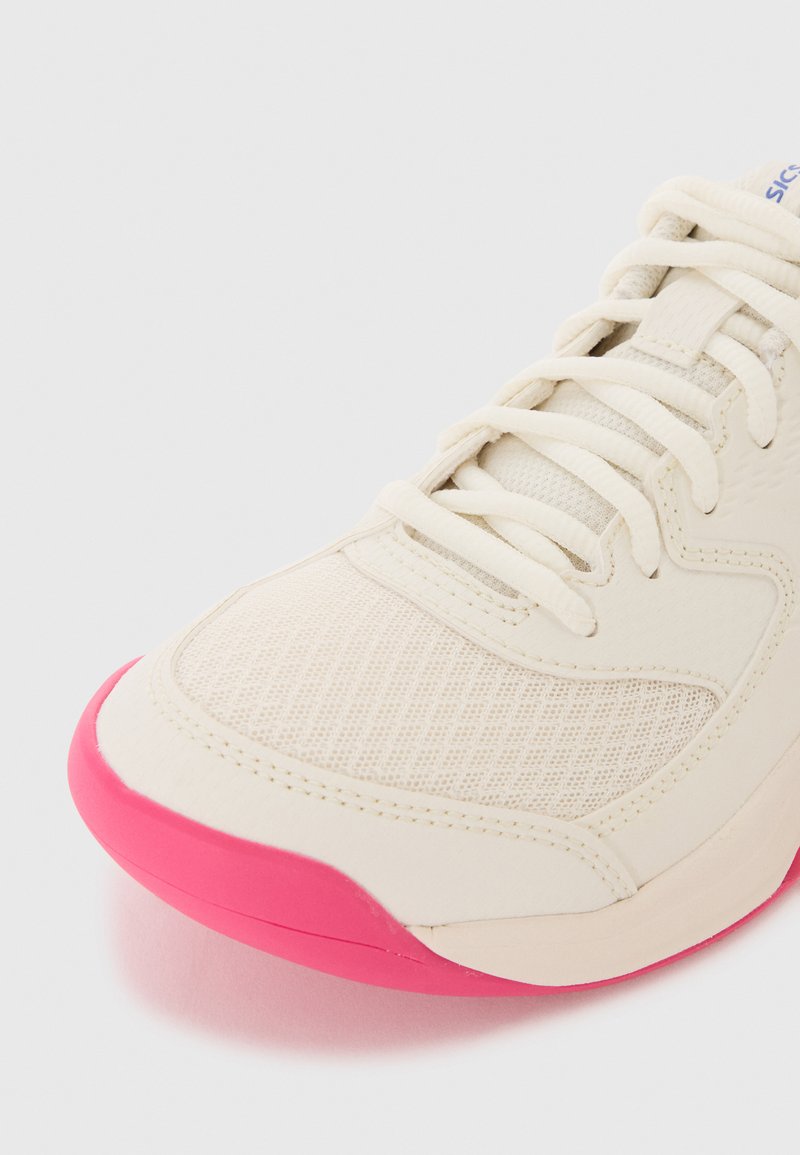 Athletic shoe with a light beige mesh upper, textured accents, and a bright pink sole. Features classic lace-up design.