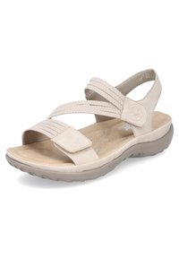 Sandalia beige con diseño de tiras cruzadas en tejido texturizado, plantilla acolchada y cierre ajustable de Velcro sobre una suela de goma que proporciona soporte.