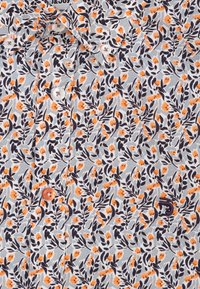 Korte mouw shirt met een lichtgrijze achtergrond met een oranje en marineblauw bloemenpatroon. Inclusief witte en oranje knopen. Katoenen stof.