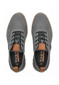 Graue atmungsaktive Schuhe mit einem strukturierten Mesh-Obermaterial, elastischen Schnürsenkeln, braunen Lederakzenten und einer Gummisohle. Größenetikett sichtbar im Inneren.