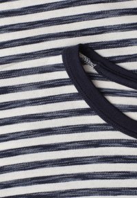 Gros plan d'un tissu tricoté rayé bleu marine et blanc avec un col rond côtelé bleu marine.