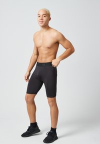 Pantaloni sportivi neri realizzati in tessuto elasticizzato con una ampia cintura elastica. Presentano un design aderente e cuciture piatte per il massimo comfort.