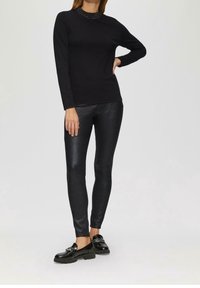 Zwarte longsleeve top met een gestructureerde halslijn, gecombineerd met glanzende zwarte legging met een subtiele sprankeling en zwarte loafers.