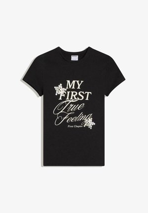 Sort T-shirt med korte ærmer med hvid tekst "MY FIRST True Feeling First Chapter" og to klynger af hvide pailletter formet som stjerner.
