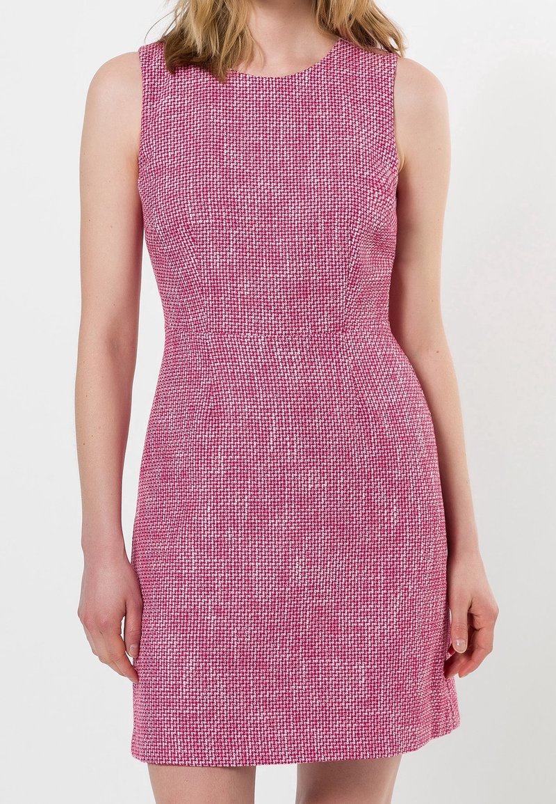 Robe texturée rose sans manches avec une taille cintrée portée par une personne sur un fond clair uni.