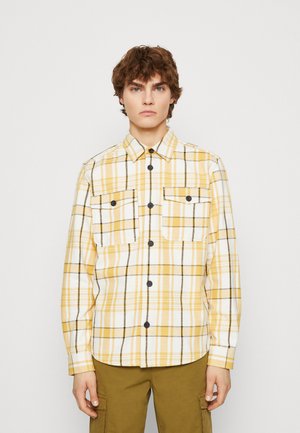 Geel en wit geruite shirt met zwarte accenten, twee voorzakken, knoopsluiting en lange mouwen. Gemaakt van een textured stof.