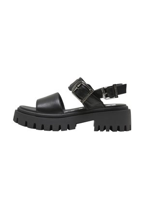 Sort chunky platformsandal med tyk sål med slidmærker, bred frontrem og justerbare dobbelte spænder ved ankel og hæl.