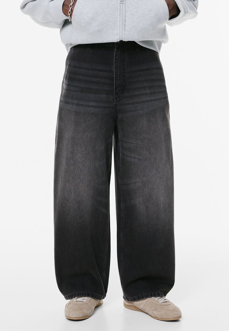 Leveled black jeans dengan pencucian memudar, terbuat dari denim. Fitur termasuk pinggang tinggi dan detail jahitan horizontal yang halus.