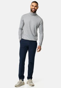 Gray turtleneck sweater paired with navy chinos, finished with light-colored sneakers. Smooth texture, fitted design with long sleeves.
