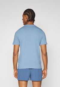 Lyseblå t-skjorte med korte ermer og rund hals, sammen med blå shorts. Stoffet ser jevnt ut med en avslappet passform.