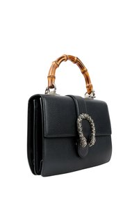 Sac à main en cuir noir avec poignée en bambou et fermoir décoratif en argent en forme de fer à cheval sur fond blanc.