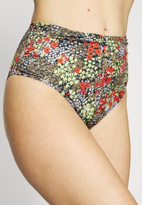 Fundo de bikini de cintura alta com um padrão floral preto apresentando flores vermelhas, verdes e brancas; tecido texturizado com cós elástico.