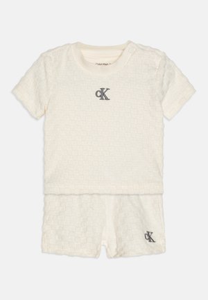 Dwuczęściowy zestaw z krótkim rękawem w kolorze ecru, wykonany z teksturowanej tkaniny. Posiada tłoczone kwadratowe wzory oraz haftowane logo "CK" w kolorze granatowym.