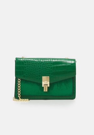 Zielona prostokątna torebka z klapką o fakturze krokodyla, złotym zapięciem i złotym łańcuszkowym paskiem na białym tle.