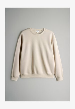 Sudadera beige con cuello redondo, puños y dobladillo acanalados, confeccionada en tejido suave, presenta un corte relajado y un diseño minimalista.