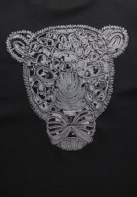 Motif de visage de léopard argenté brodé et orné de sequins sur tissu noir, présentant des taches et contours détaillés.