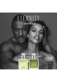 Calvin Klein Eternity dufter flasker, en i gult og en i grønt, med klart kvadratisk design og metalliske detaljer, mot en svart bakgrunn.