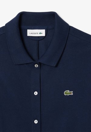 Polo blu navy con colletto a coste, abbottonatura con tre bottoni e piccolo logo di coccodrillo verde ricamato sul petto.