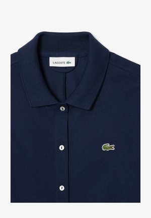 Navy blue polo shirt with a ribbed collar, three button placket, and small green crocodile logo embroidered on the chest.