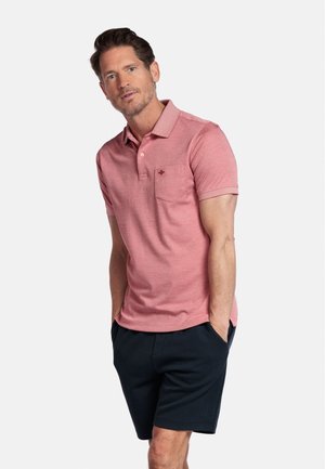 Polo rose à manches courtes et col, avec une poche poitrine. Associé à un short bleu marine, offrant un look décontracté.