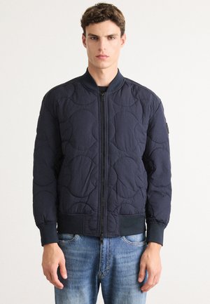 Navy quilted bomber jacket with a zipper front, ribbed cuffs, and collar. Features a smooth texture and subtle circular stitching pattern.