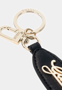 Portachiavi in pelle sintetica nera con gancio a scatto in metallo color oro e anello circolare, con un dettaglio decorativo del logo dorato.