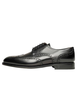 Chaussure habillée en cuir noir avec un design à bout fleuri et des perforations, lacets plats et un petit talon. Texture lisse avec une finition brillante.