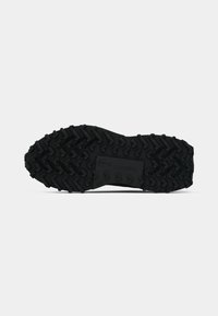 Talpa de sneaker din cauciuc negru, cu un model de profil robust și diferite forme de aderență, detaliu cu logo în relief, suprafață texturată pentru tracțiune.