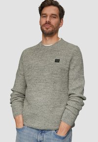 Szary sweter dziany z okrągłym dekoltem, ściągaczami na rękawach i małą czarną łatą z logo na piersi. Miękka faktura, casualowy krój.