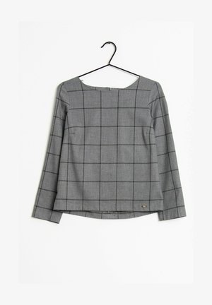 Grijze blouse met lange mouwen met zwart ruitenpatroon, boothals en klein metalen logo-label onderaan, hangend aan een zwarte kledinghanger.