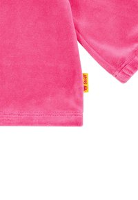 Jersey rosa hecho de tejido suave y texturizado con un acabado liso. Presenta una pequeña etiqueta amarilla de la marca en la costura lateral.