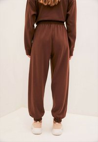 Braune, lässig geschnittene Jogginghosen mit elastischem Bund und Bündchen, aus weichem Material. Ergänzen ein lässiges Outfit.