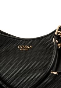 Borsa a tracolla in pelle intrecciata nera con un design semplice, logo dorato "GUESS EST 1981" e dettagli in metallo dorato.