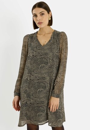 Vestido beige y negro con estampado, cuello en V y mangas largas ligeramente abullonadas, con un diseño ondulado y un ajuste relajado.