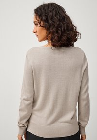 Maglione beige lavorato a maglia con maniche lunghe, scollo rotondo e polsini e orlo a coste. Texture morbida con una vestibilità rilassata.