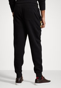 Pantaloni sportivi neri realizzati in tessuto morbido, con una vita elasticizzata, tasche laterali e una tasca posteriore con un accento logo sulla coscia.